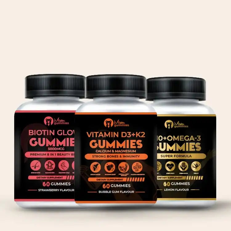 Three bottles of Mister Gummies Total Wellness Trio dietary supplements for adults: Biotin Glow Gummie (5000mcg, Strawberry flavour, for beauty), Vitamin D3 + K2 Gummies with Calcium & Magnesium (Bubble Gum flavour, for strong bones & immunity), and Q10 + Omega-3 Gummies (Lemon Flavour, Super Formula). Each bottle contains 60 gummies.